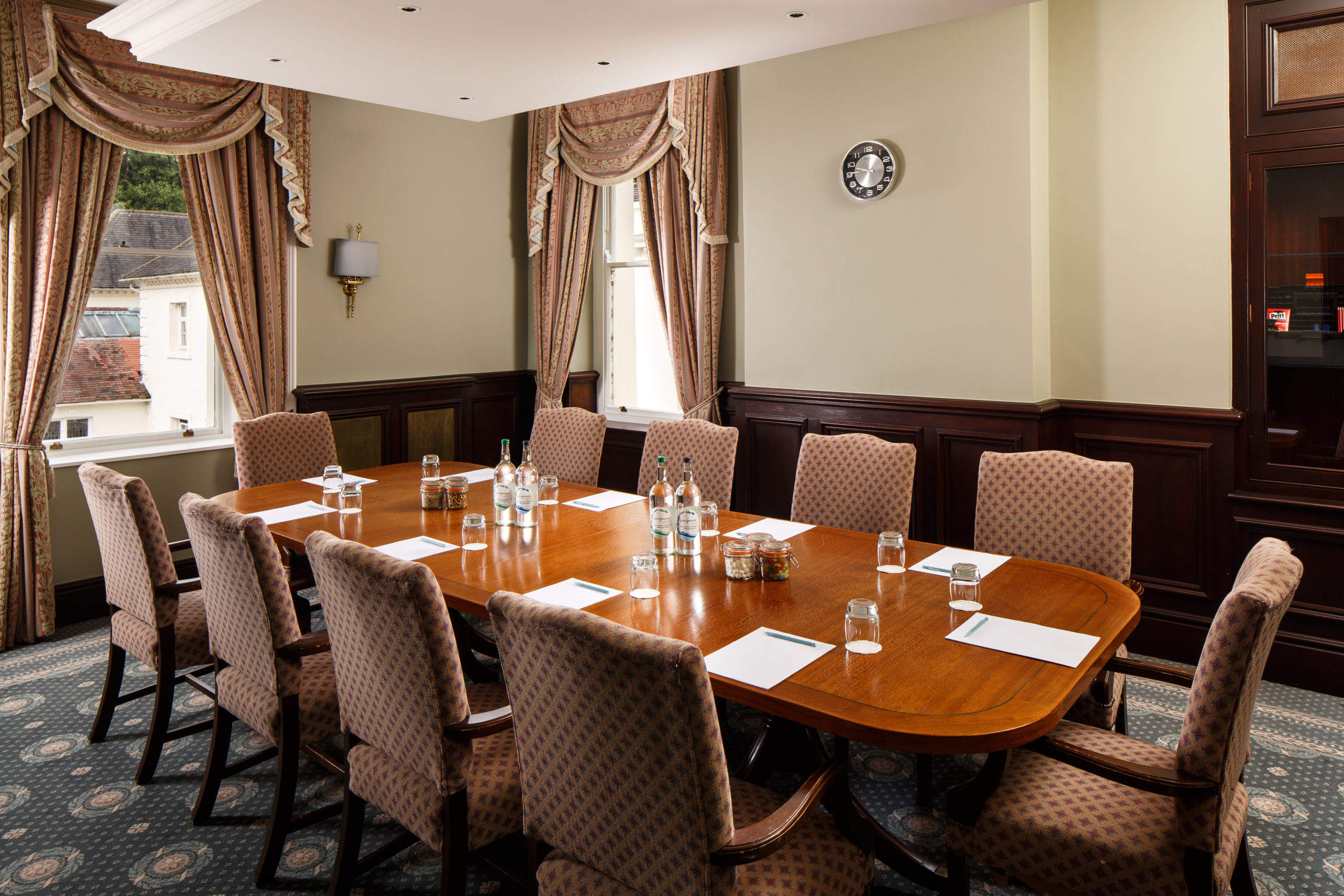 The long table seating 10 in The Boardroom at mercure gloucester bowden hall hotel ready for a meeting, with notepads and bottles of water on the table