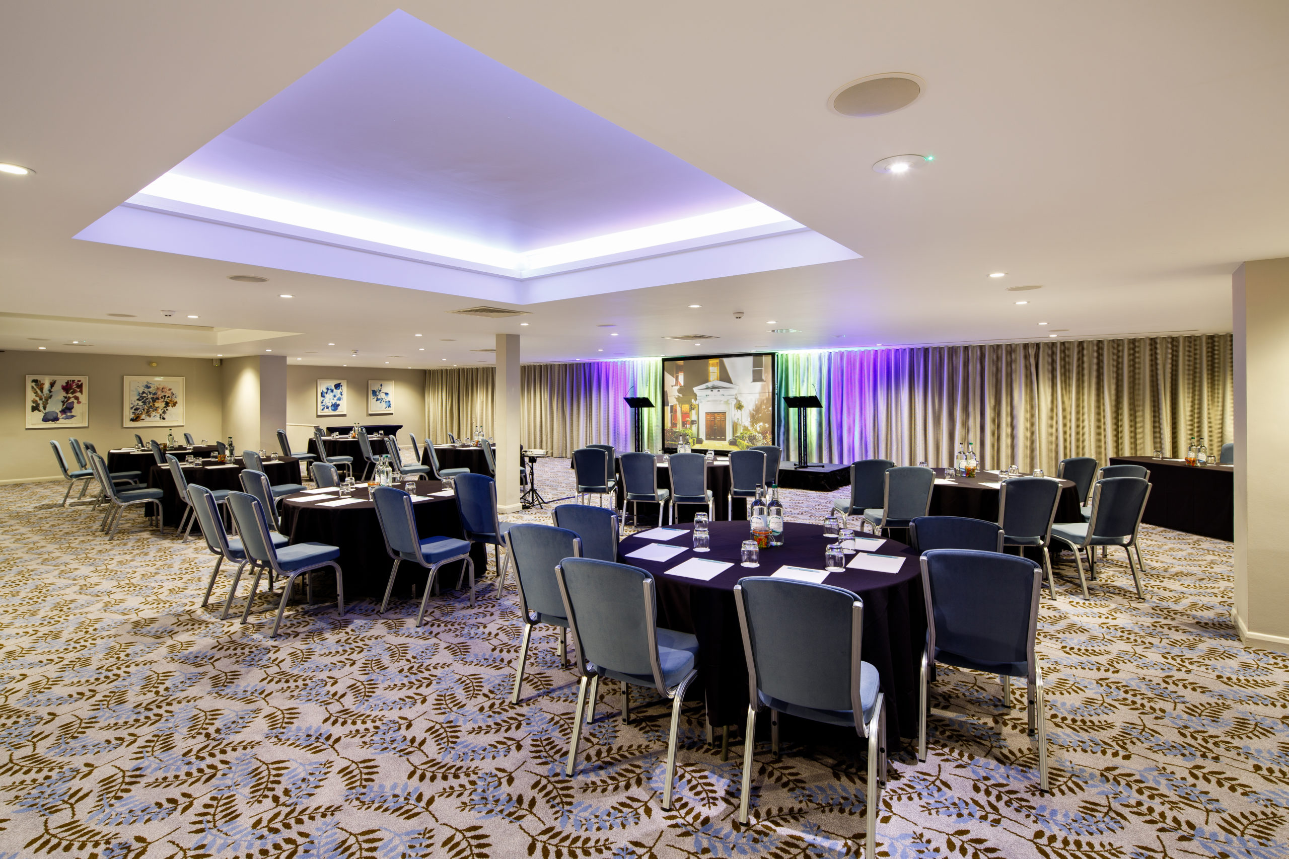 Mercure-Gloucester-hotel-meeting-rooms-Lakeside_01_h-190816 Angled view from the back of The Lakeside Suite at mercure gloucester bowden hall hotel ready for a conference and presentation on the large video screen