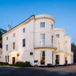 An angled view of the car park and frontage of the mercure gloucester bowden hall hotel in floodlights at dusk