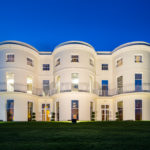 Head on view of the lawn and frontage of the mercure gloucester bowden hall hotel in floodlights at night