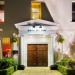Front double doors and archway with columns at mercure gloucester bowden hall hotel floodlit at night