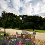 Table and four chairs next to a flower bed in the gardens at mercure gloucester bowden hall
