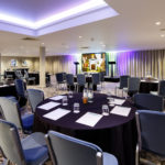 Angled view of the lakeside suite set for a conference with purple lighting at mercure gloucester bowden hall hotel