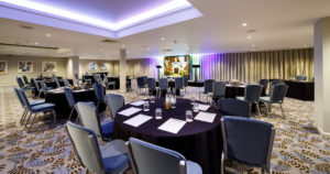 Angled view of the lakeside suite set for a conference with purple lighting at mercure gloucester bowden hall hotel