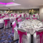 Angled view of the lakeside suite set for a wedding with pink lighting at mercure gloucester bowden hall hotel