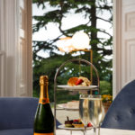 Close up of afternoon tea on a cake stand and champagne bottle with two glasses in the lounge at mercure gloucester bowden hall hotel