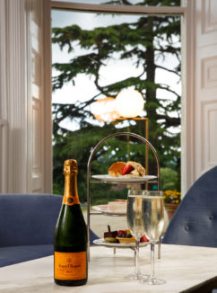 Close up of afternoon tea on a cake stand and champagne bottle with two glasses in the lounge at mercure gloucester bowden hall hotel